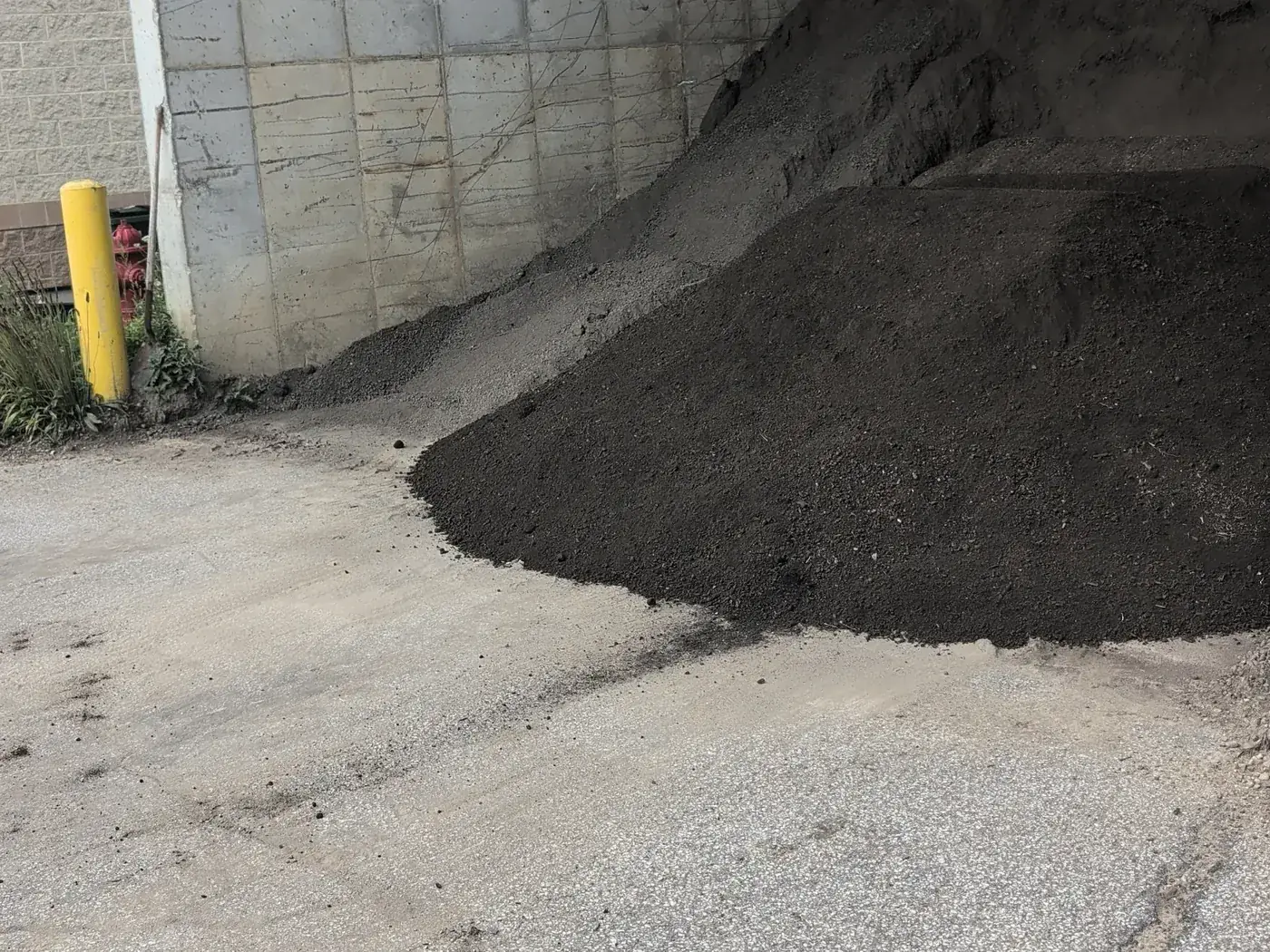Two stockpiles of dark material in the concrete loading bays at the yard