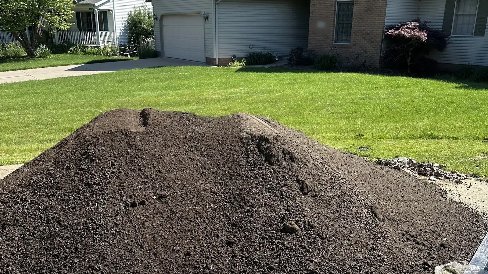 A delivered pile of topsoil in front of a home